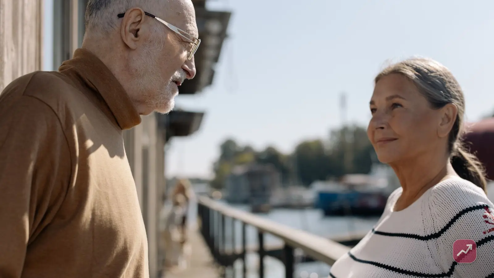 A relaxed retired couple talking by a marina — the comfortable retirement that tax-advantaged accounts like a 401(k), IRA or Roth are built to fund.