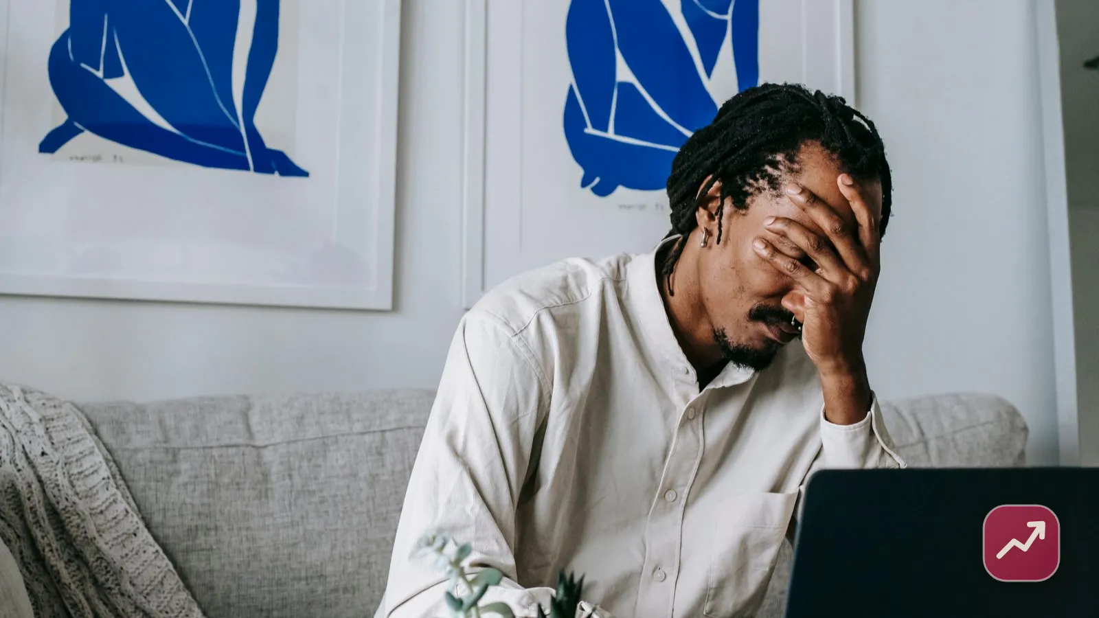 A worried man at home resting his head in his hand in front of his laptop, illustrating the stress of dealing with debt collectors and knowing your rights.