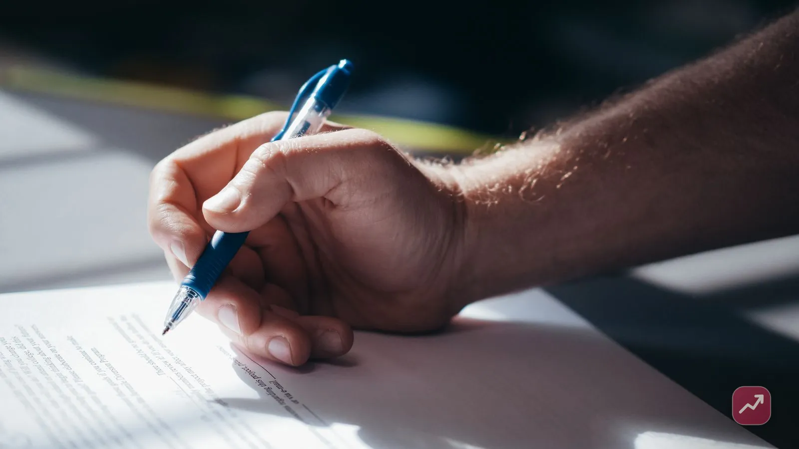 A person signing a will document with a pen at a desk, illustrating the basics of estate planning — deciding who inherits and who cares for dependents.