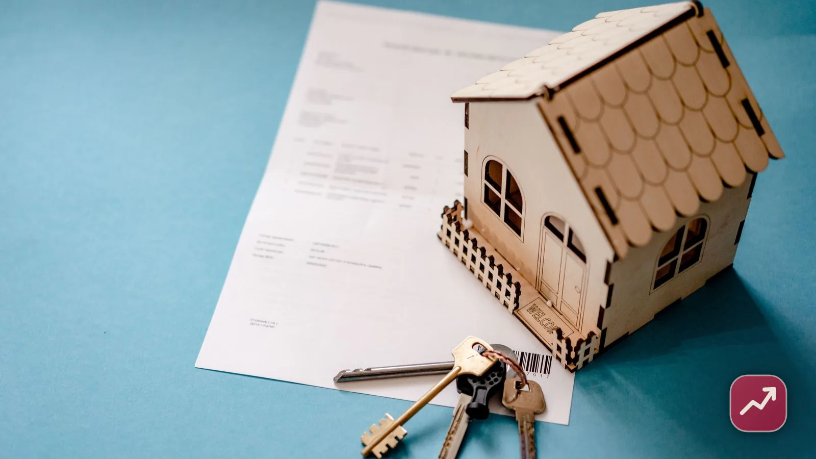 Una casa de madera en miniatura con unas llaves sobre un contrato de préstamo, que ilustra pedir dinero con la vivienda como garantía hipotecaria.