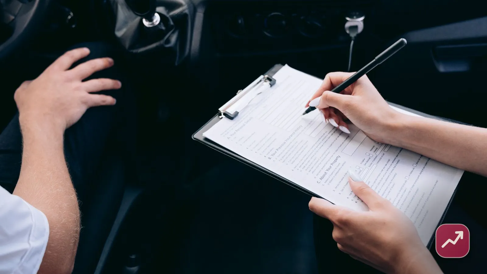 A person signing a car insurance document on a clipboard inside a car, illustrating how liability, collision and comprehensive coverage work.