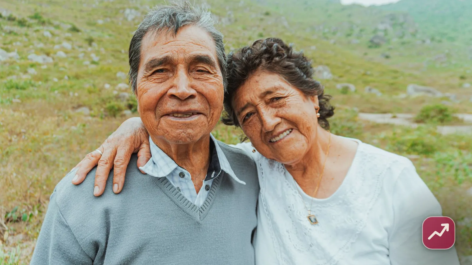 A happy retired couple embracing outdoors in a green landscape, illustrating how to turn savings into a lasting retirement income.