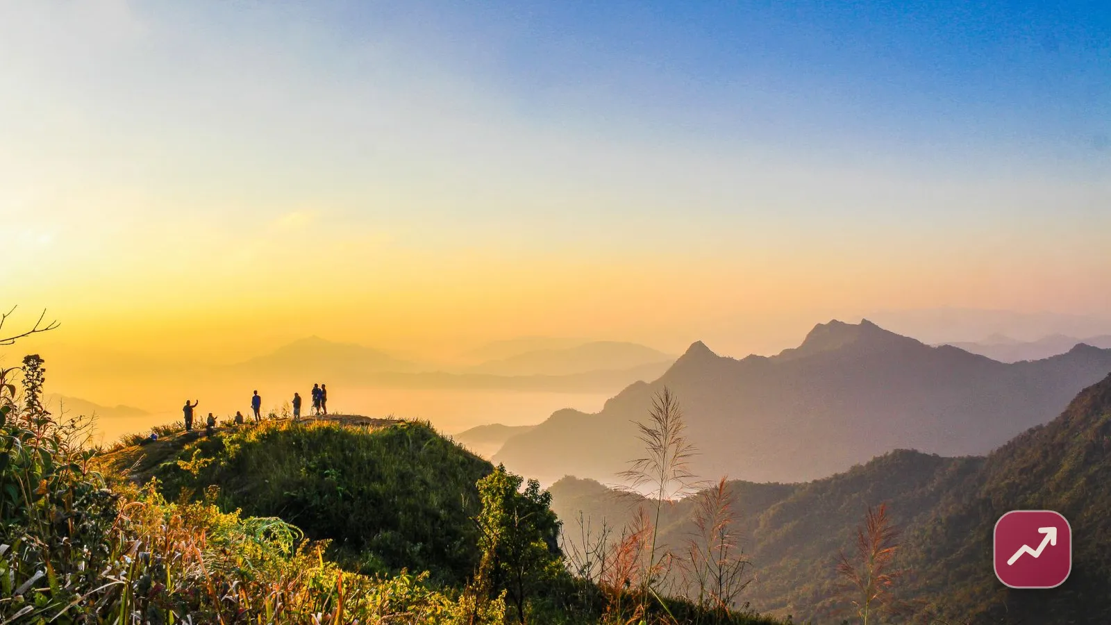 People standing on a mountain summit at sunrise taking in the view, illustrating the freedom of early retirement and financial independence (FIRE).