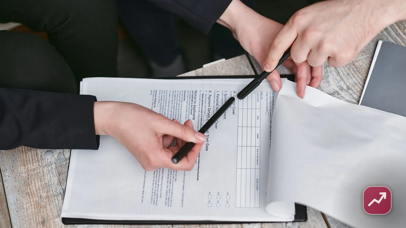 Two people signing a legal document with pens at a table, illustrating setting up a power of attorney to decide who manages your money if you lose capacity.