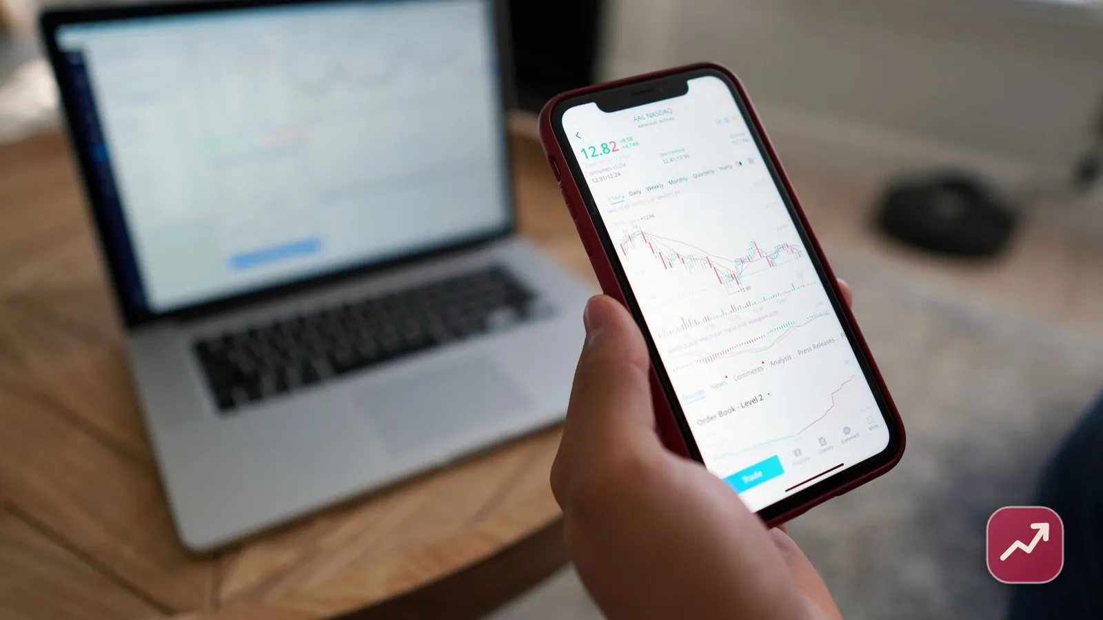 A young investor reviewing an automated robo-advisor portfolio and its low fees on a phone and laptop.