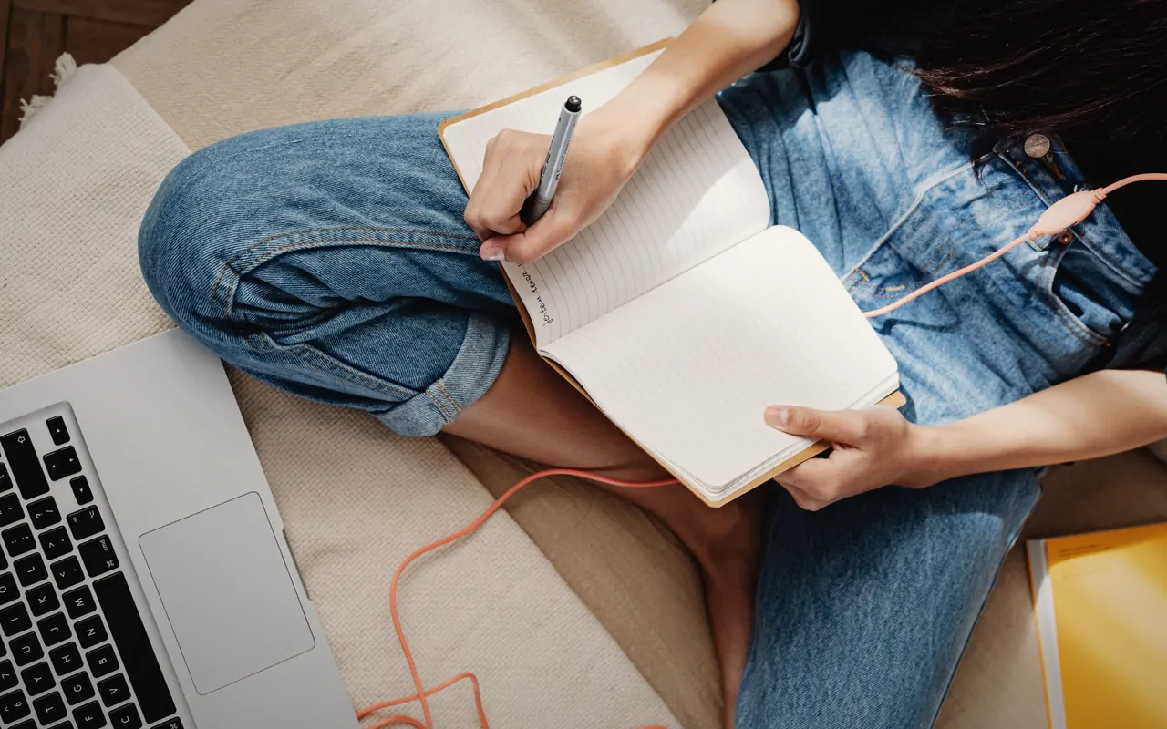 Persona tomando notas delante de un portátil mientras aprende a invertir