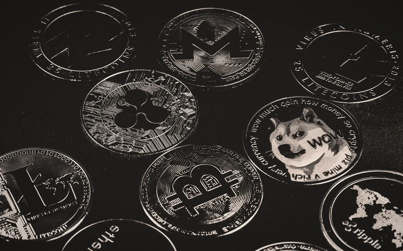 Monedas físicas de Bitcoin y de otras criptomonedas sobre una mesa oscura