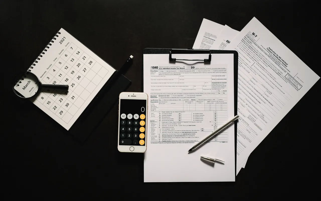 Calculadora, documentos y un portátil sobre una mesa, listos para preparar la declaración de la renta