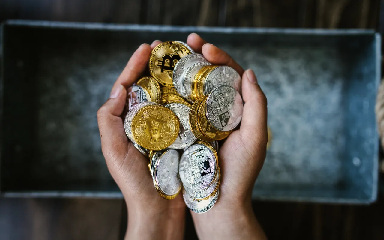 Monedas de criptomonedas sobre una mesa oscura junto a un gráfico de precios