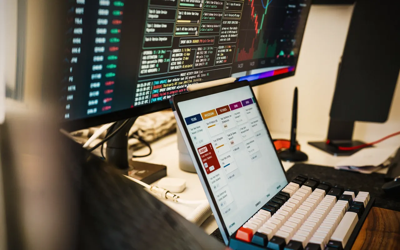 Monitor con un gráfico de velas japonesas e indicadores de trading en una habitación a oscuras